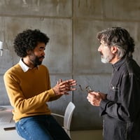 Two colleagues talk in the office, collaborating on a solution.