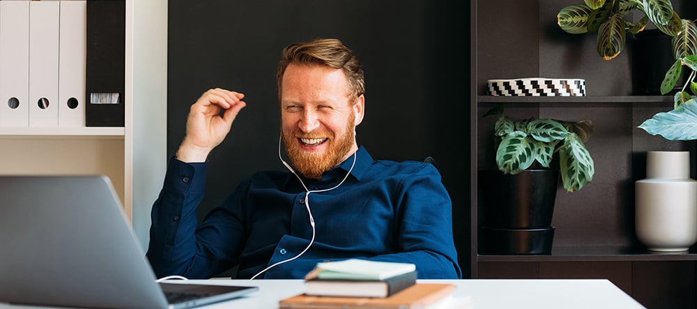 A young man laughing during a digital meeting.