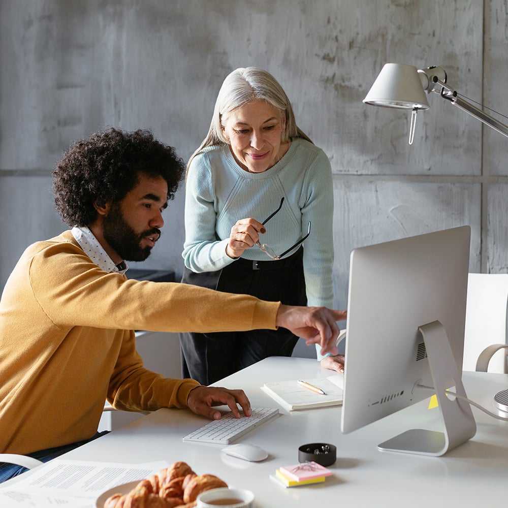 Two colleagues collaborating at a computer, analyzing what’s on-screen.