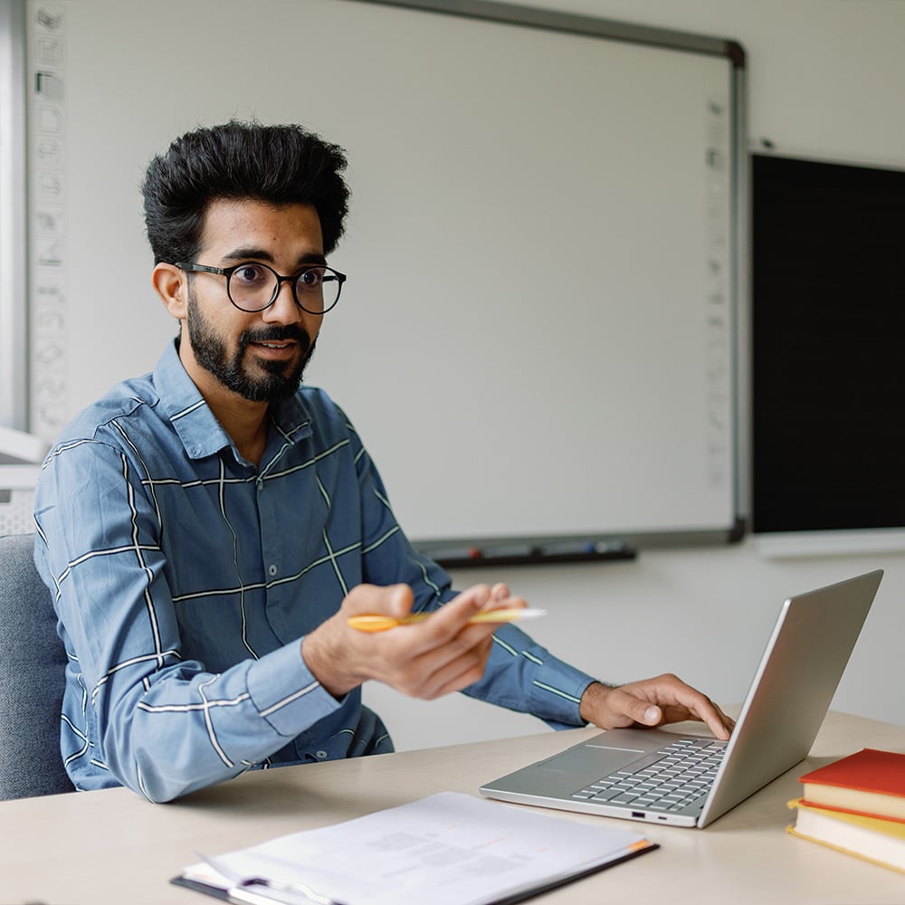 A school teacher makes a presentation from his laptop.