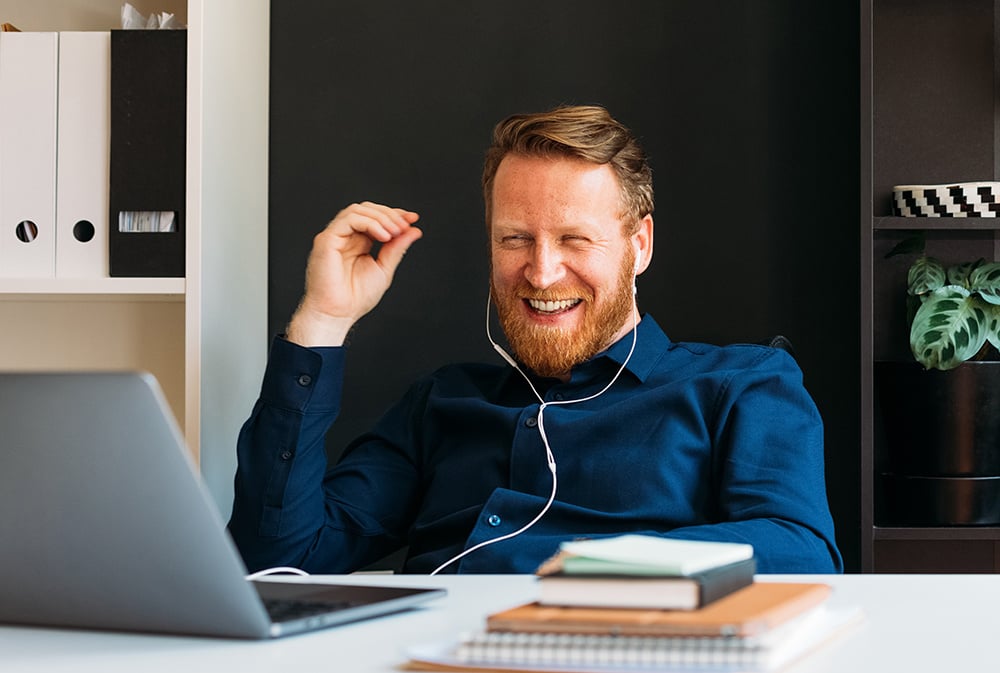 A young man laughing during a digital meeting.